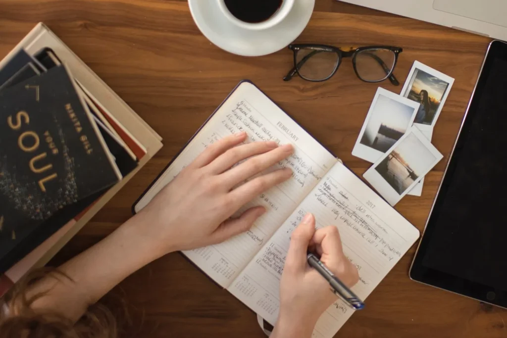 Écriture thérapeutique : une femme écrit dans un carnet, vue de dessus