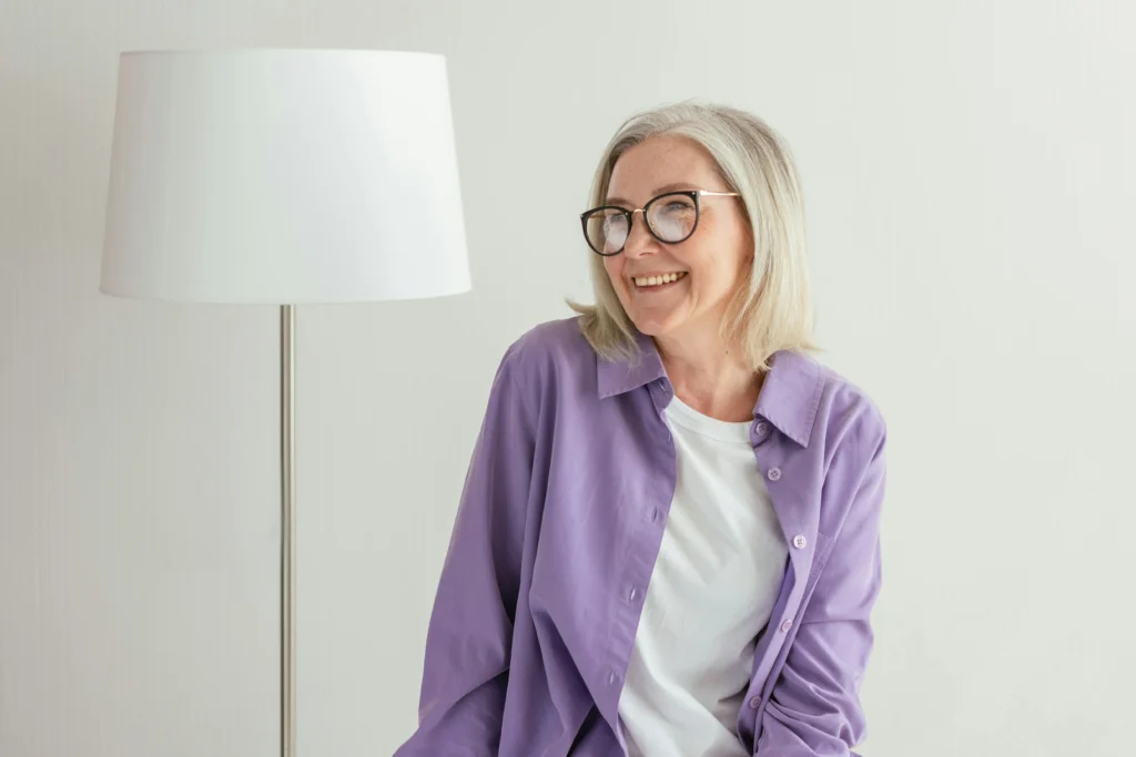 écrire son histoire personnelle : une femme senior avec une chemise violette sourit en regardant de côté